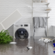 This photo shows a room containing a washing machine and items from home that has flooded, with water standing and items floating in water.